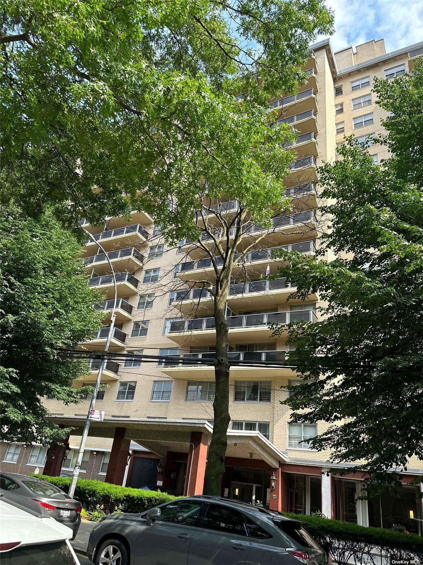 a front view of a building with lot of trees