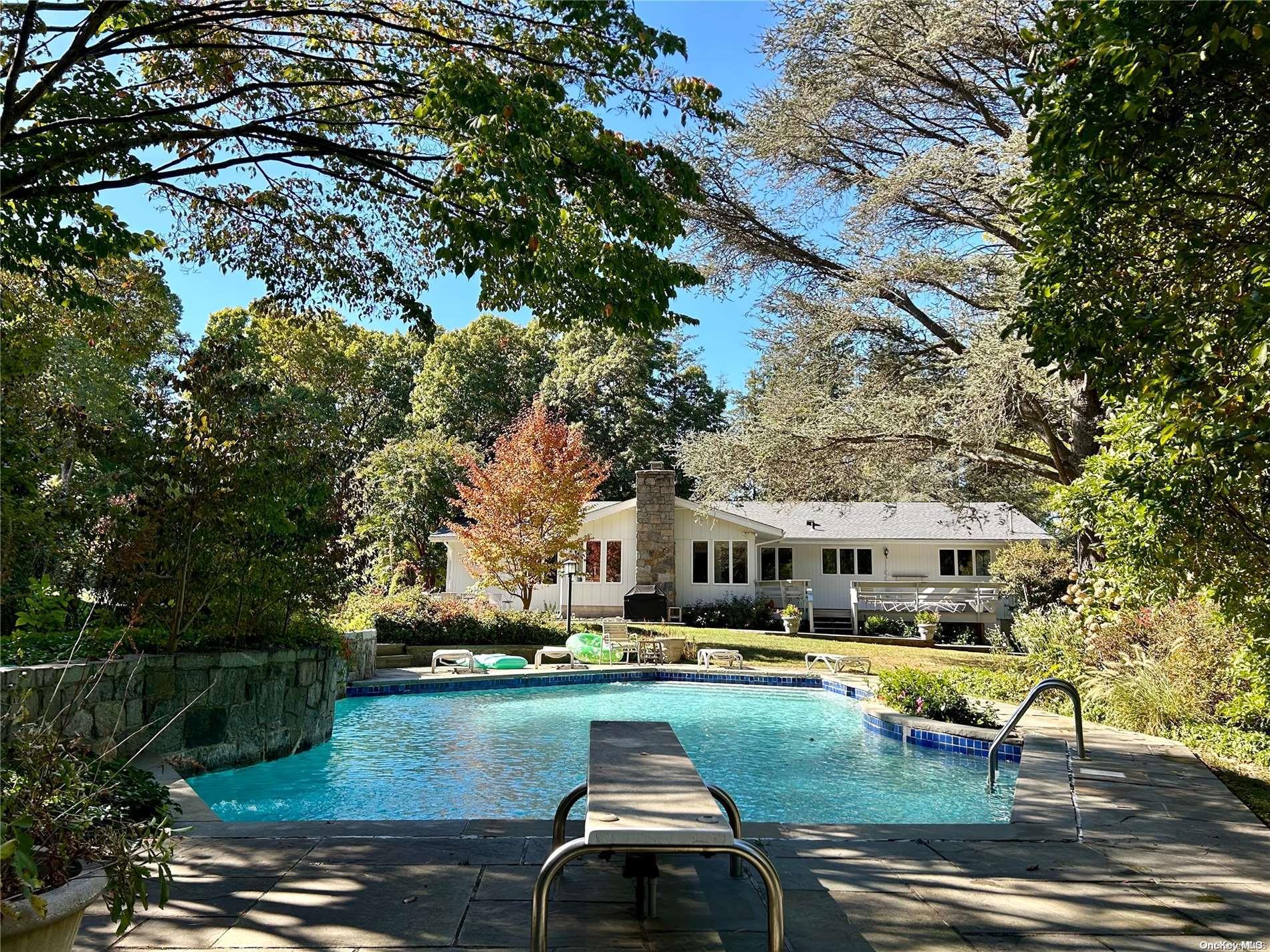 a view of swimming pool with outdoor seating and trees in the background