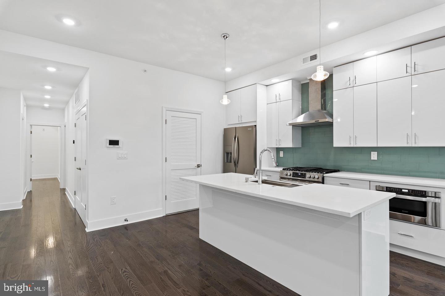 a kitchen with stainless steel appliances white cabinets and wooden floor