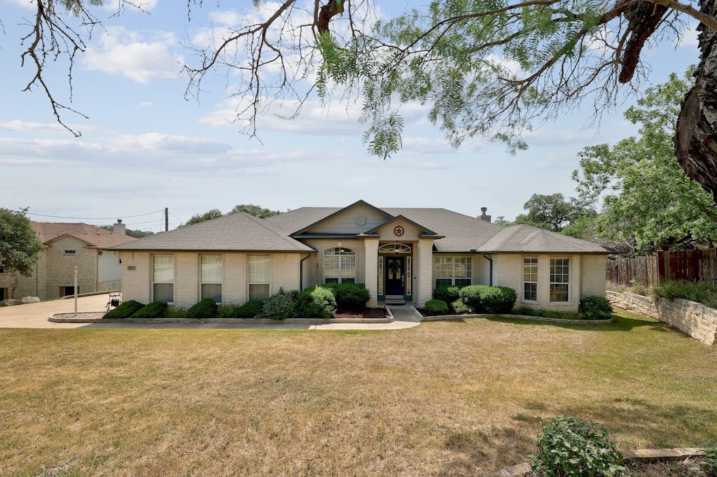 a front view of a house with a yard and trees