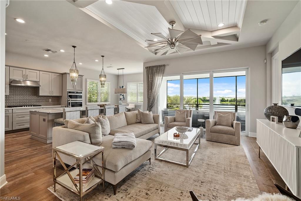 a living room with furniture kitchen view and a chandelier