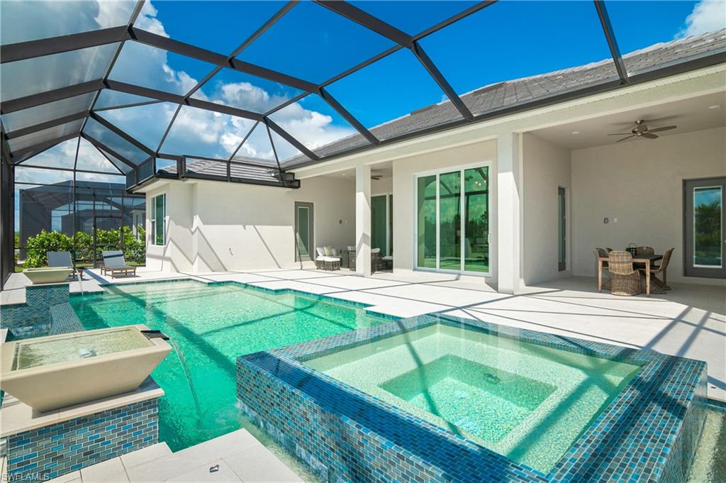 View of swimming pool with glass enclosure, an in ground hot tub, a patio area, and ceiling fan