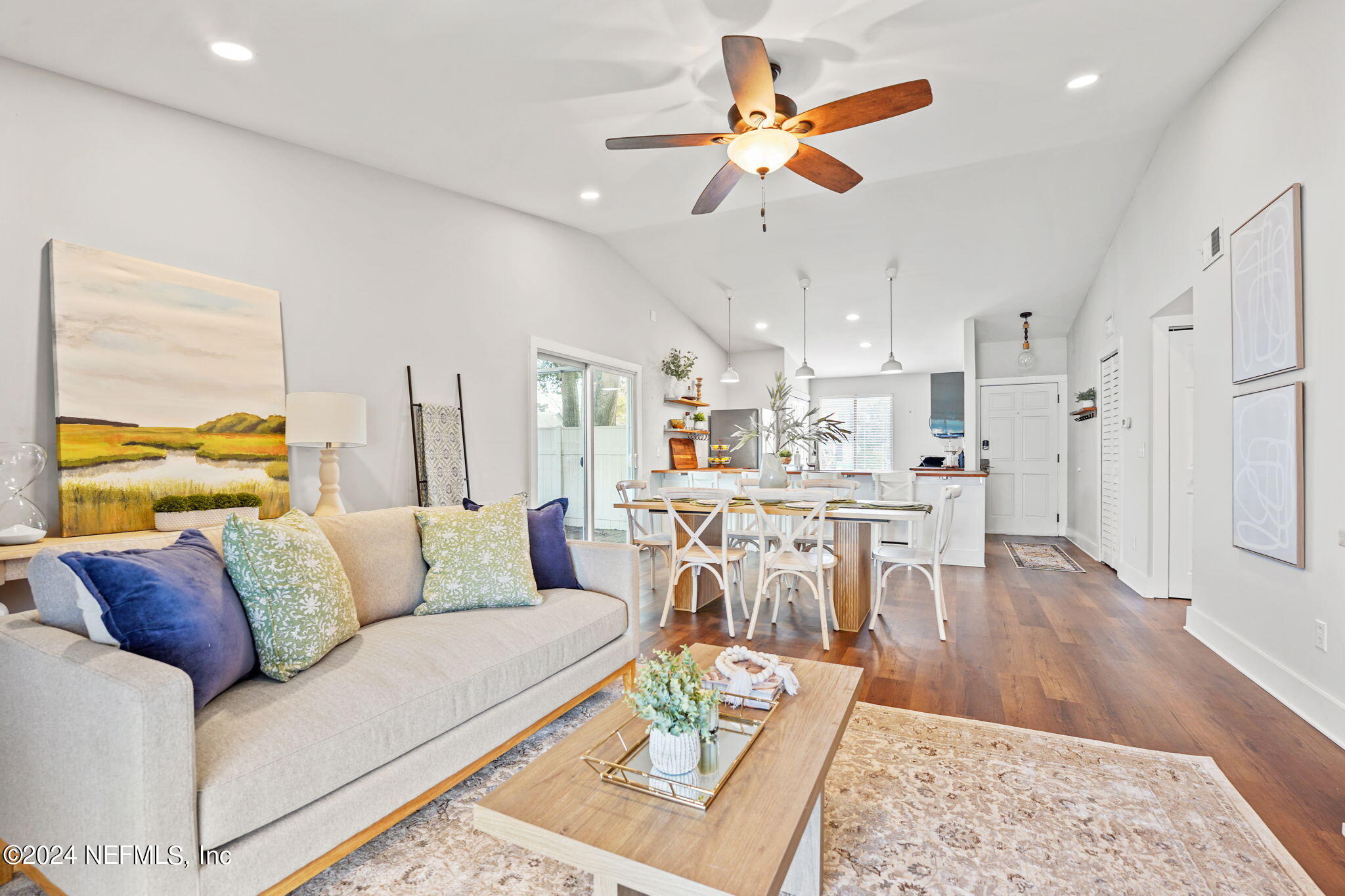 a living room with furniture kitchen view and a wooden floor