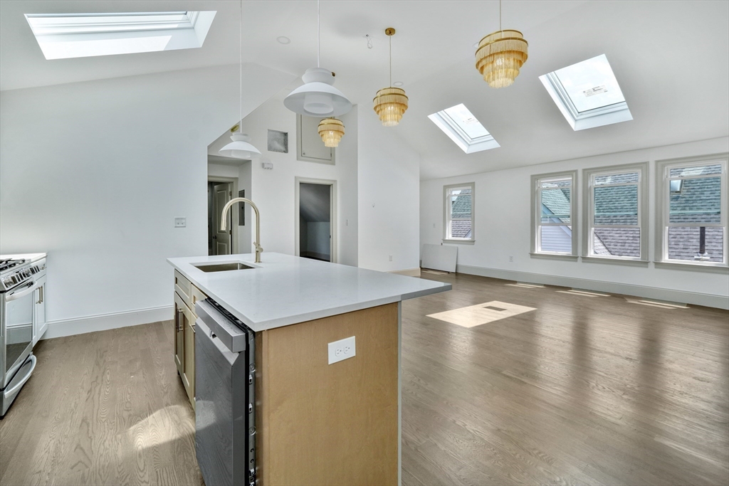 a view of a kitchen with a sink dishwasher stove and a dining table with wooden floor