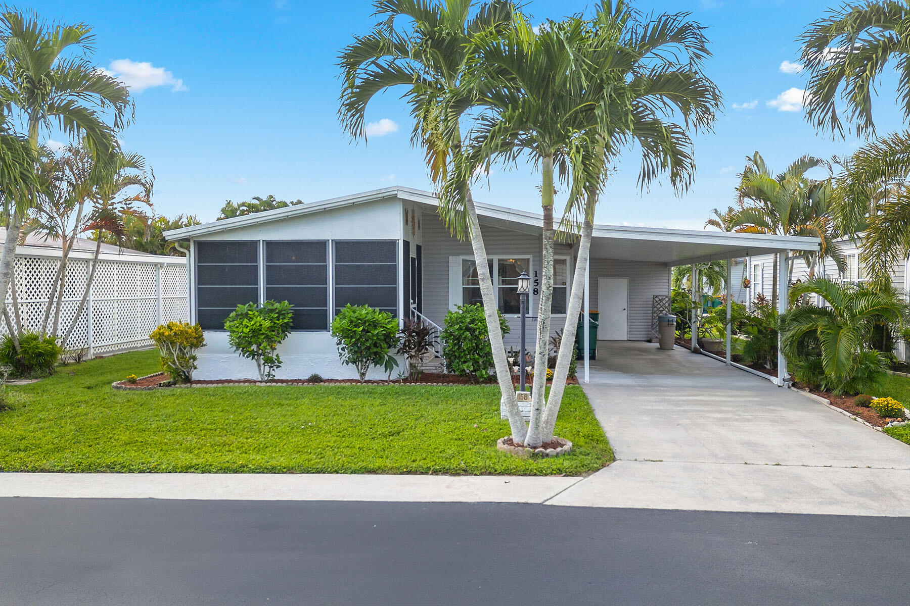 a front view of a house with a yard and palm trees