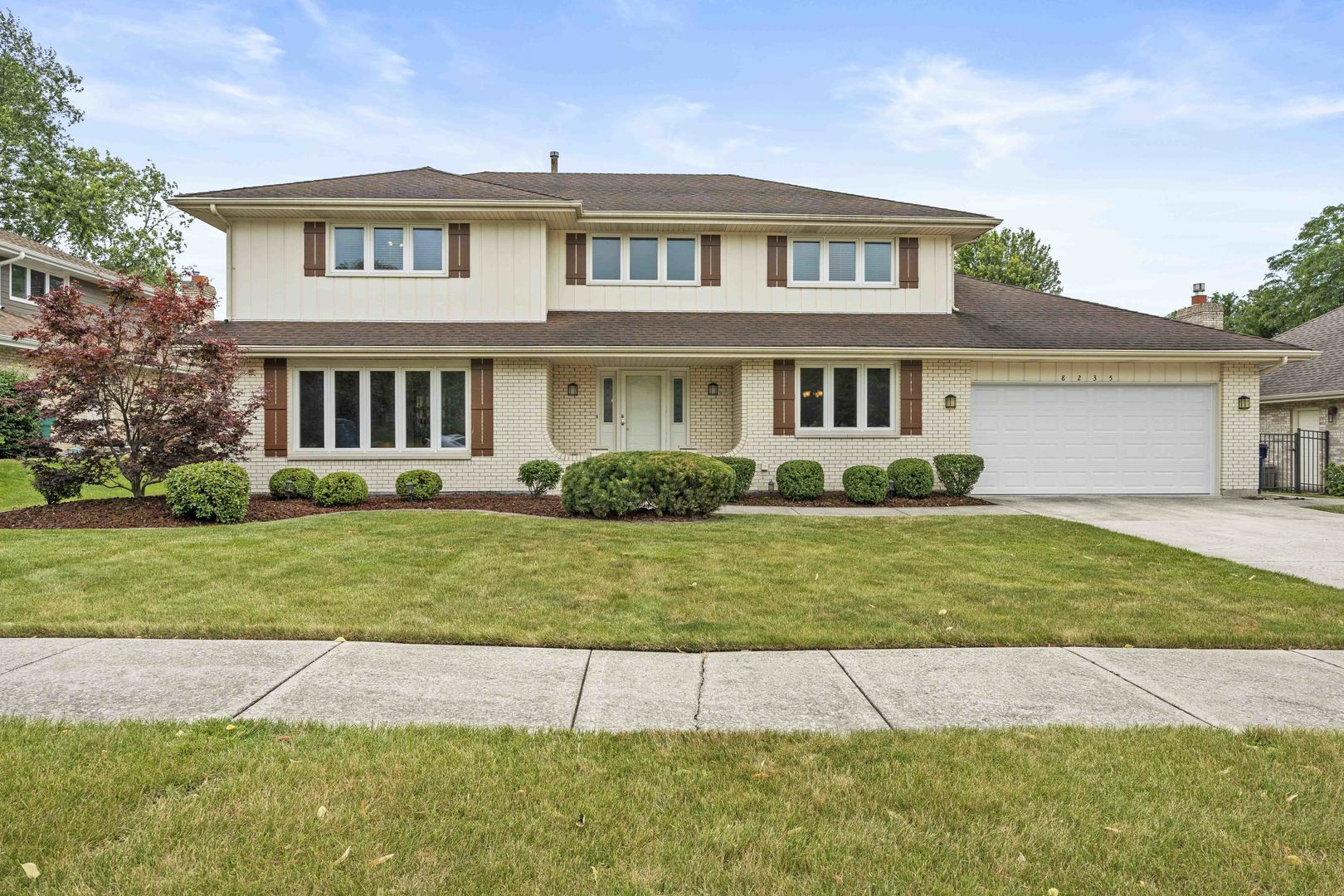 a front view of a house with a yard and trees