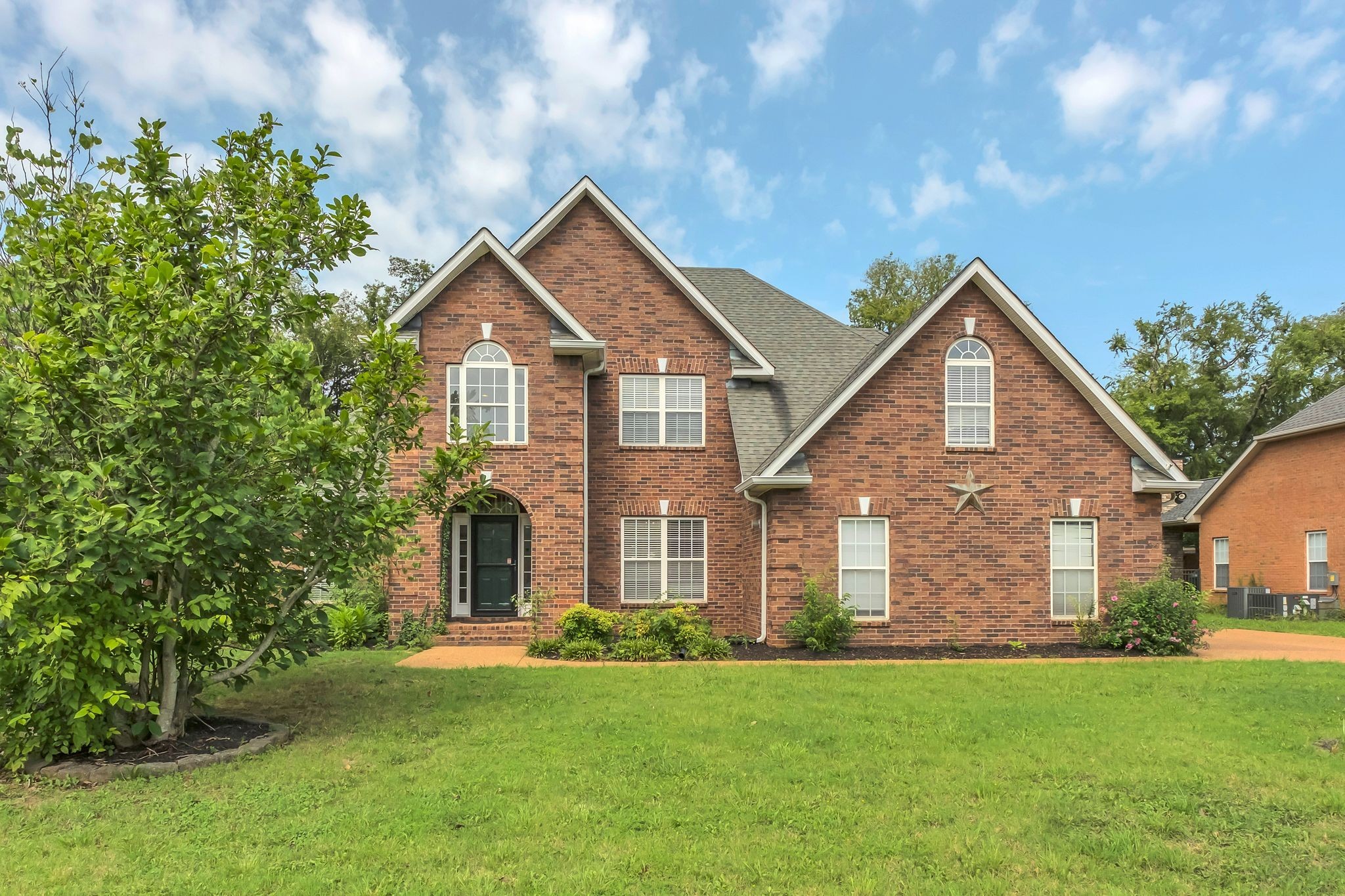 a front view of a house with a yard and trees