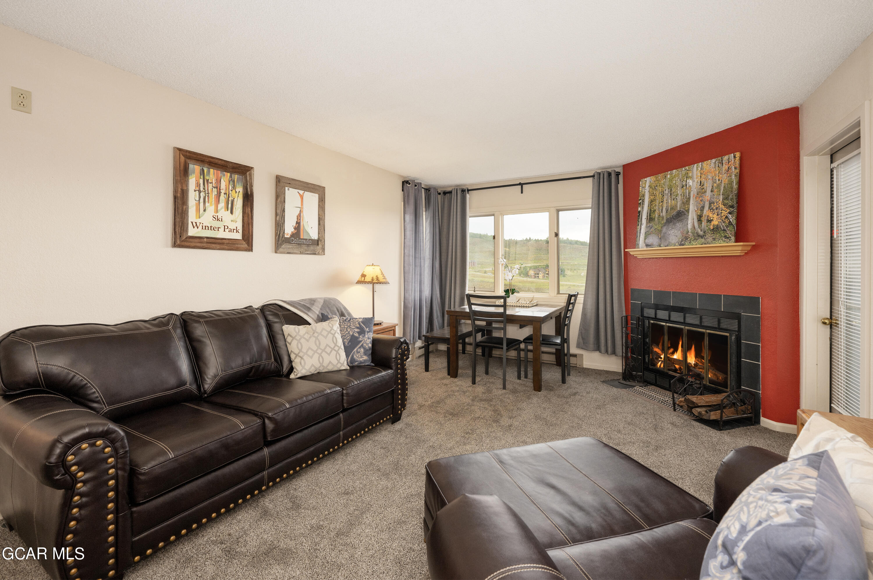 a living room with furniture a fireplace and a large window