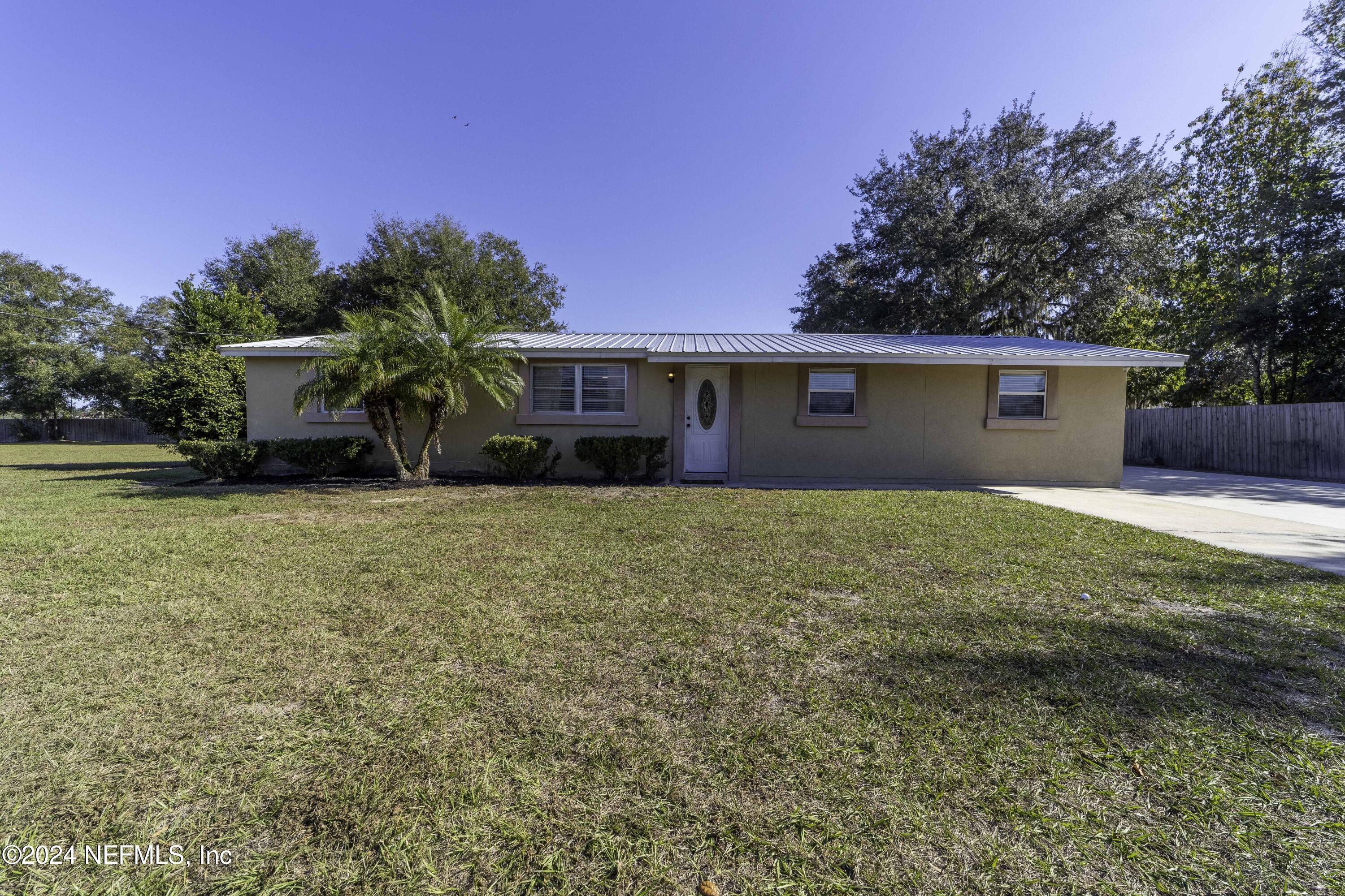 a front view of house with yard and trees in the background