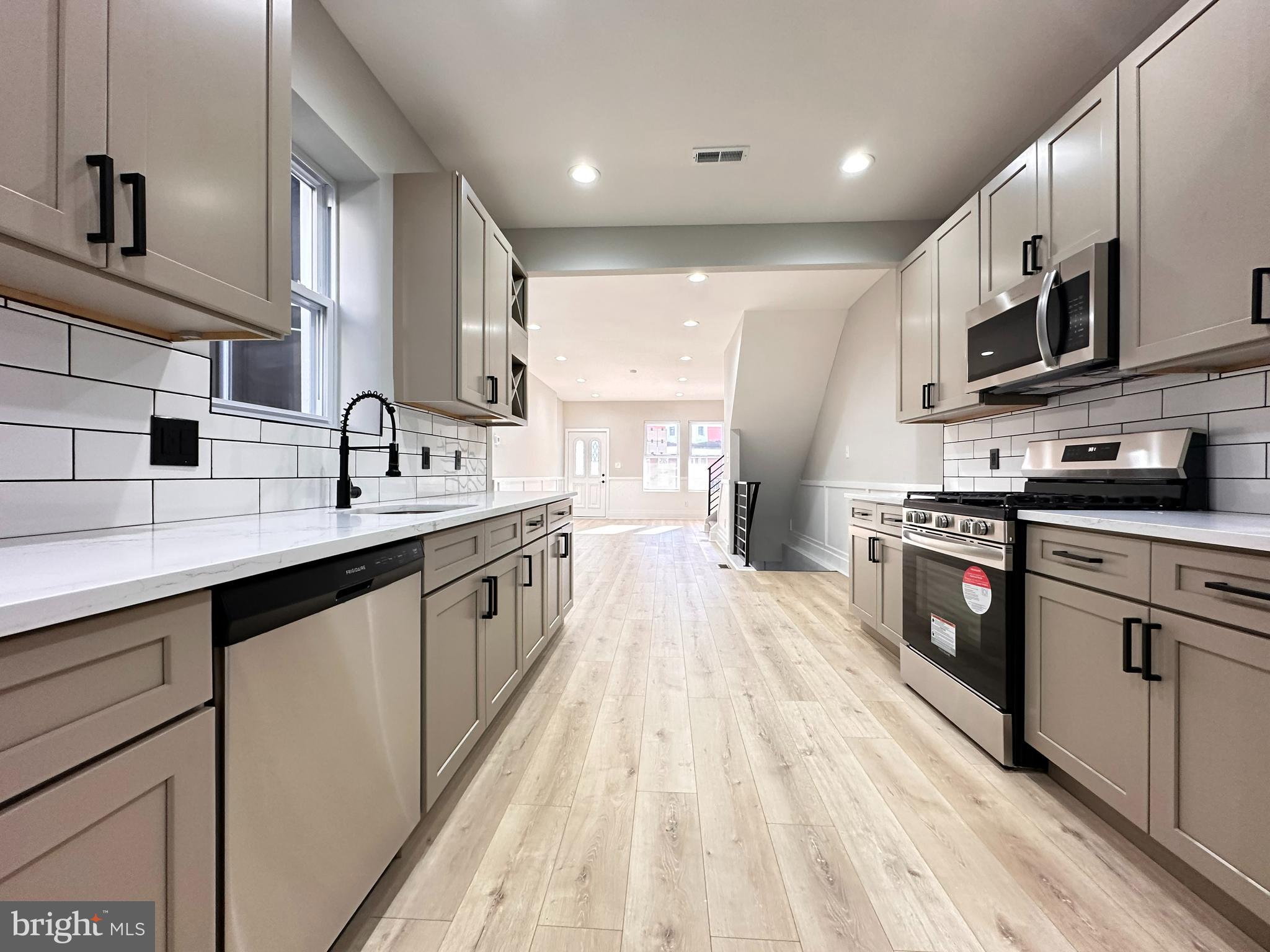 a large kitchen with stainless steel appliances double sink stove top oven and cabinets