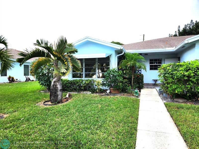 a front view of a house with a yard and potted plants