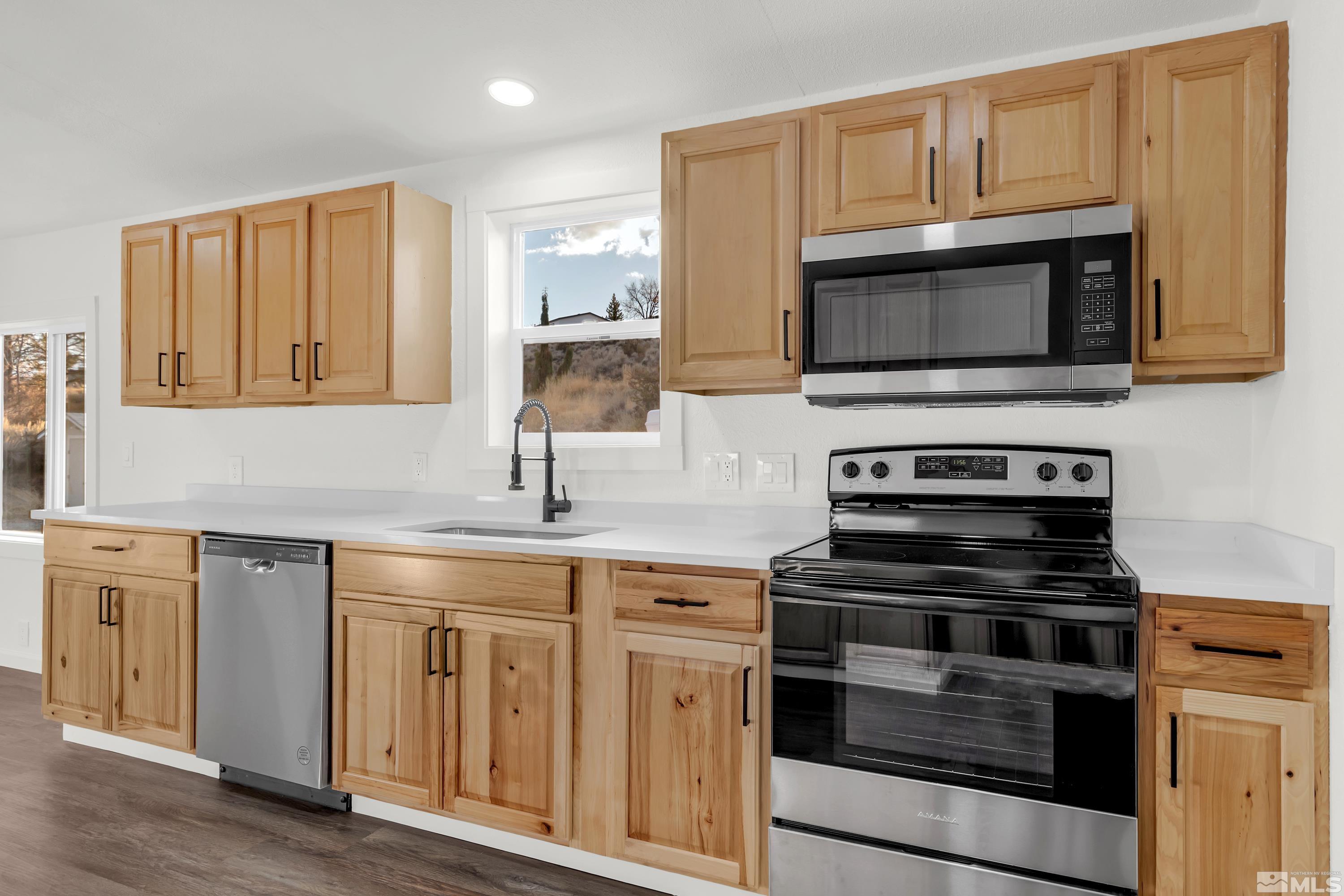 a kitchen with cabinets stainless steel appliances and wooden floor