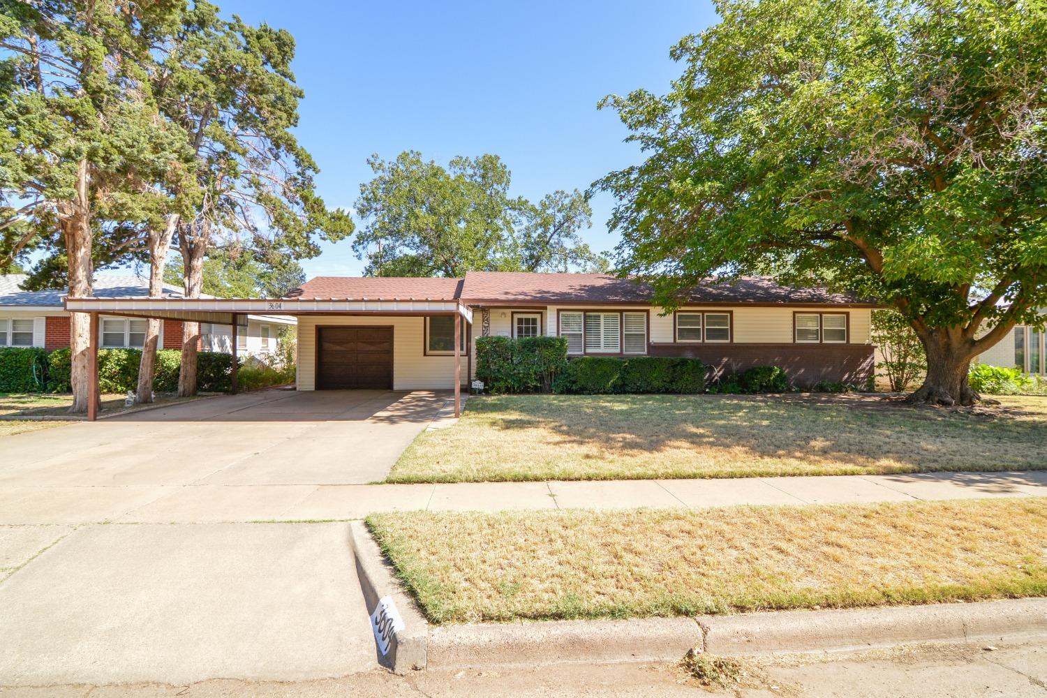 a view of a house with a yard and large tree