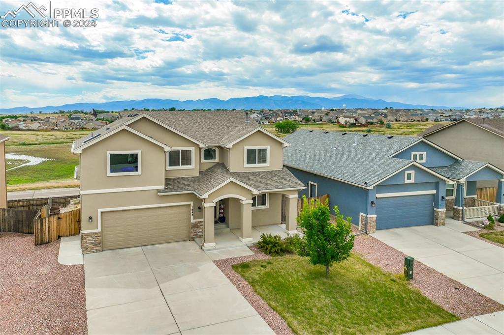 View of front of property featuring a 3car tandem garage and mountain range views