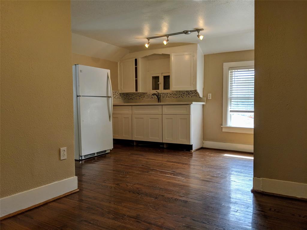 a view of a kitchen with a sink a refrigerator wooden floor and a window