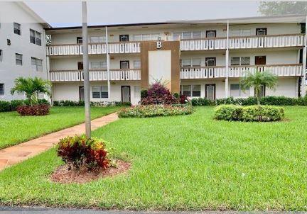 a front view of a building with a garden and plants