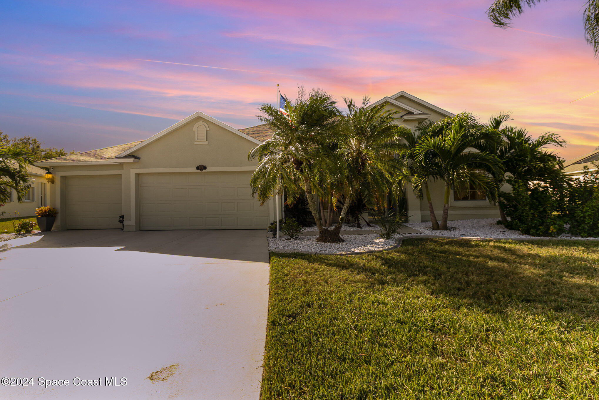 a view of a house with a yard and palm trees