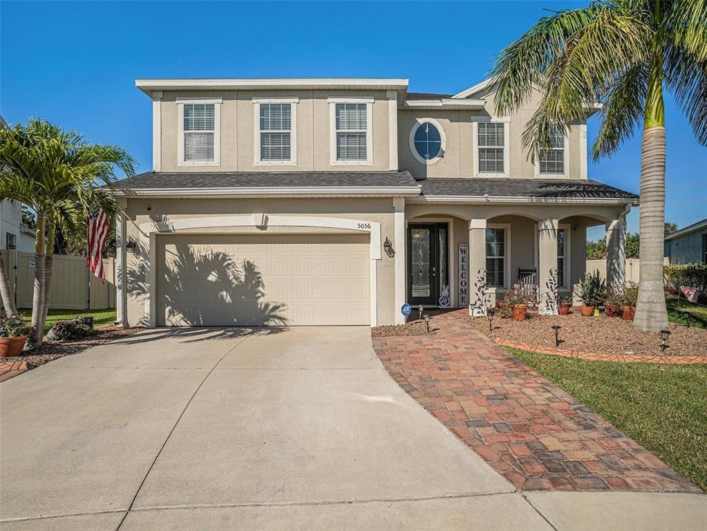 front view of a house with a yard and palm trees