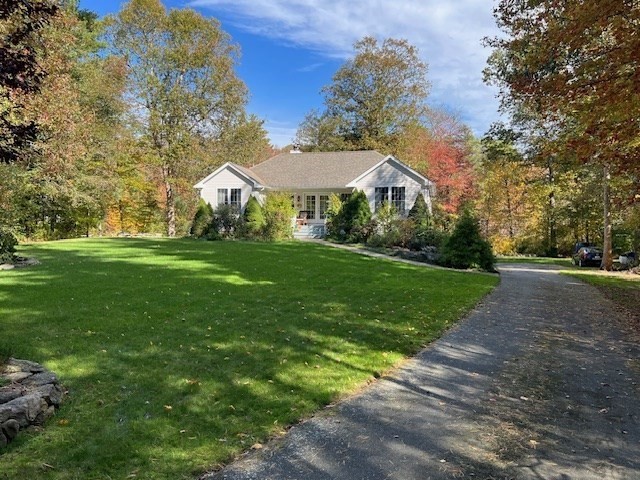 a view of a big yard in front of a brick house with large trees