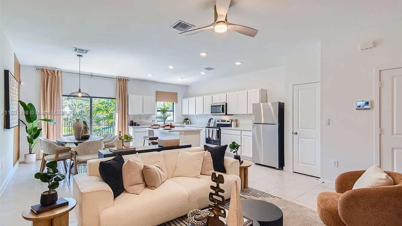 a living room with stainless steel appliances furniture and a large window