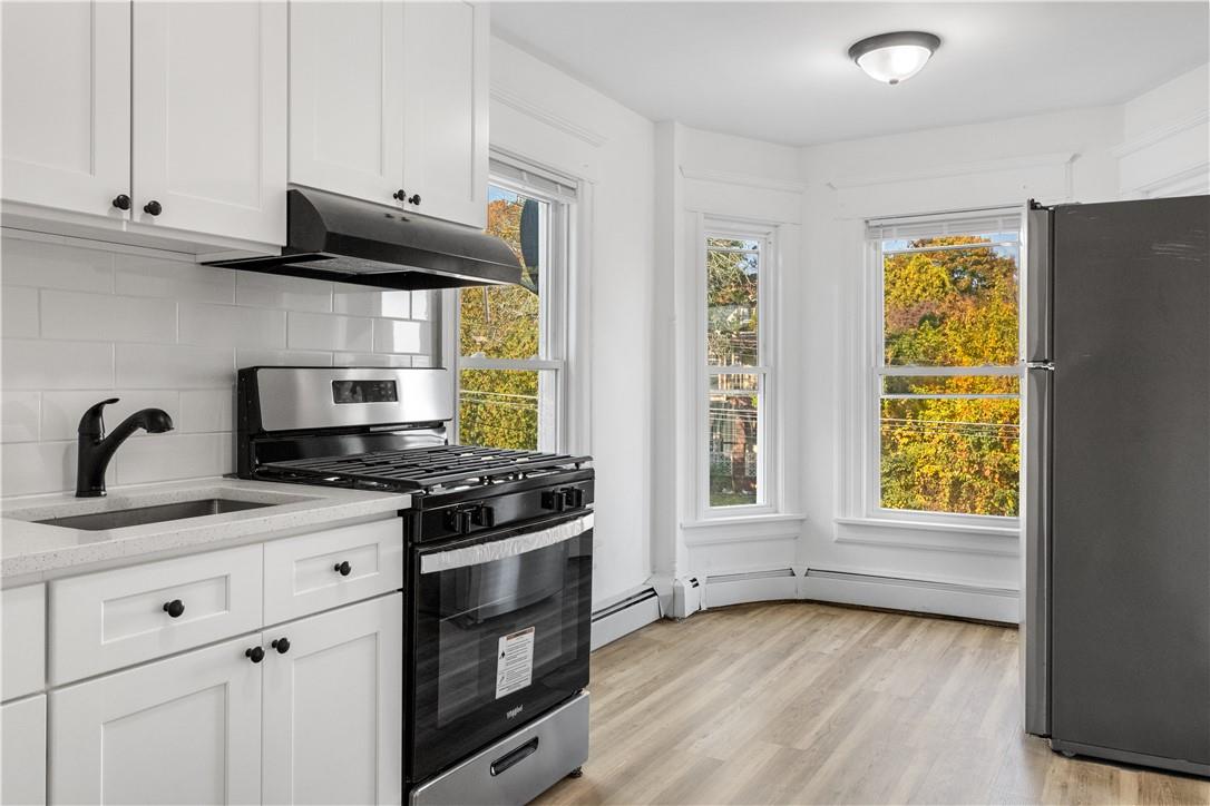 Kitchen with appliances with stainless steel finishes, light wood-style flooring, white cabinetry, and sink