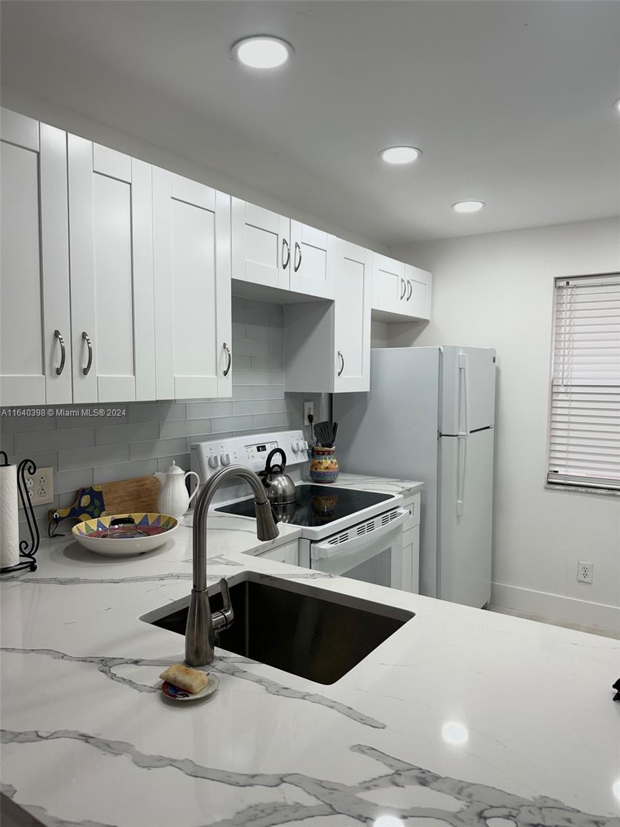 a kitchen with granite countertop a sink stainless steel appliances and cabinets