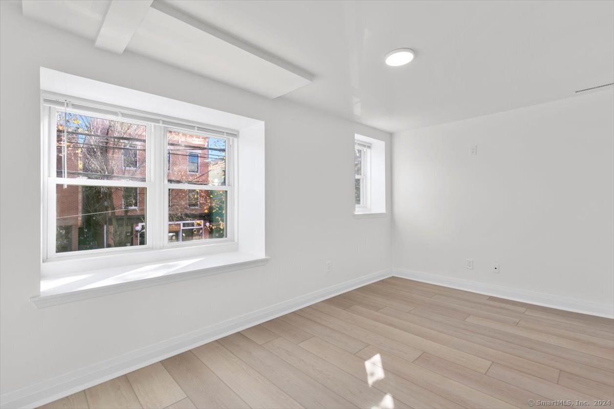 an empty room with wooden floor and windows