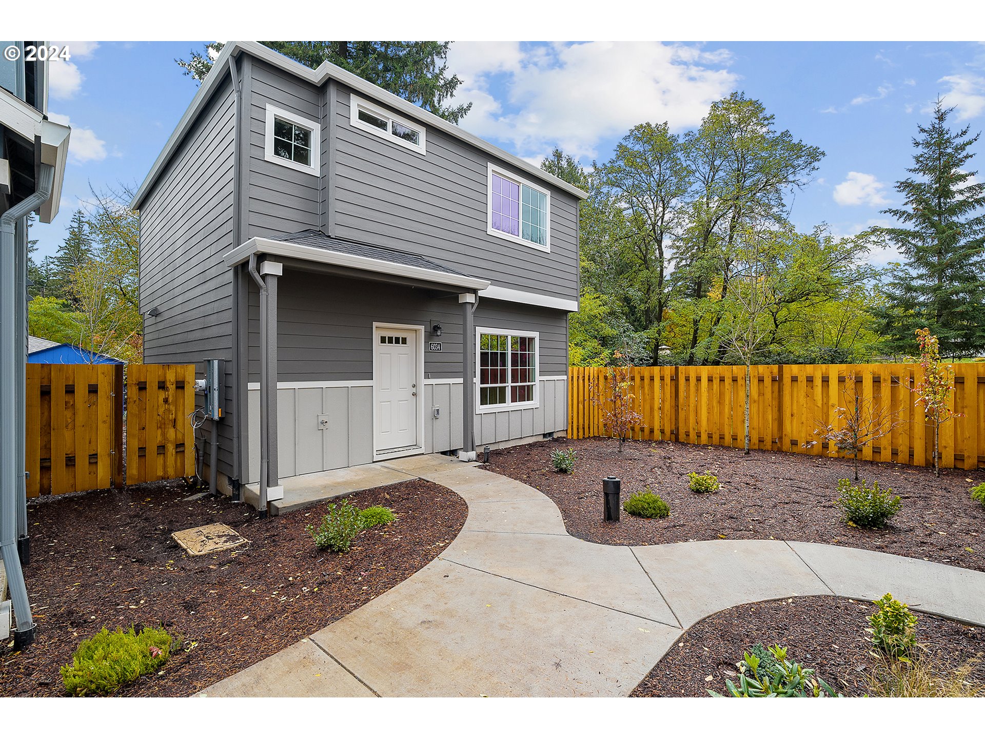 a view of a backyard with a large tree and wooden fence