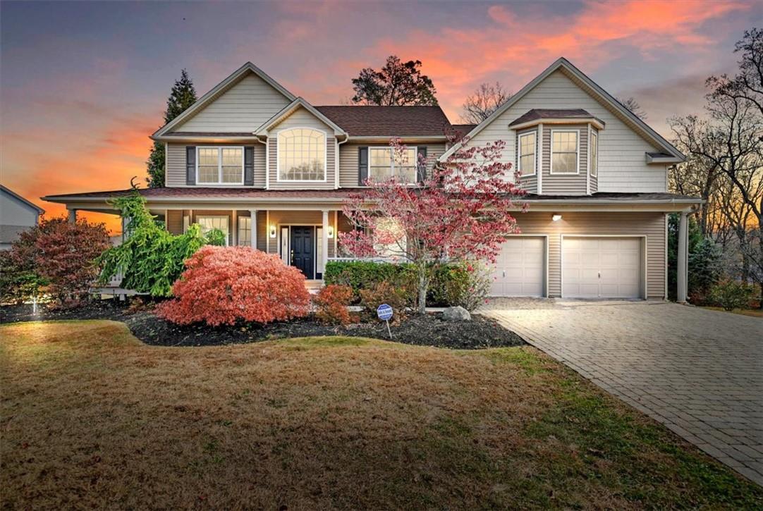 View of front of property with a lawn and a 2 attached garage with spacious driveway and mature landscape.