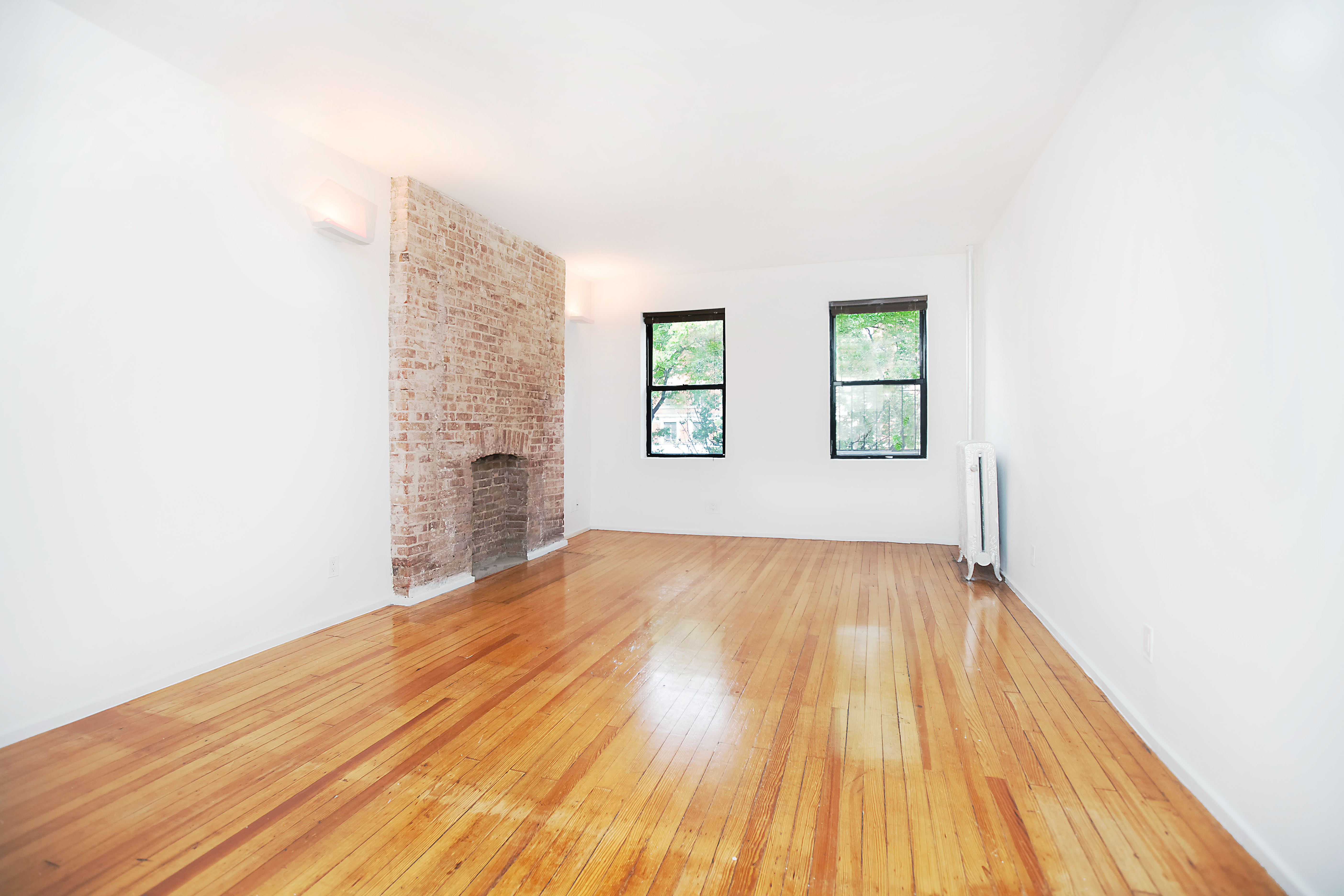 a view of a big room with wooden floor and windows