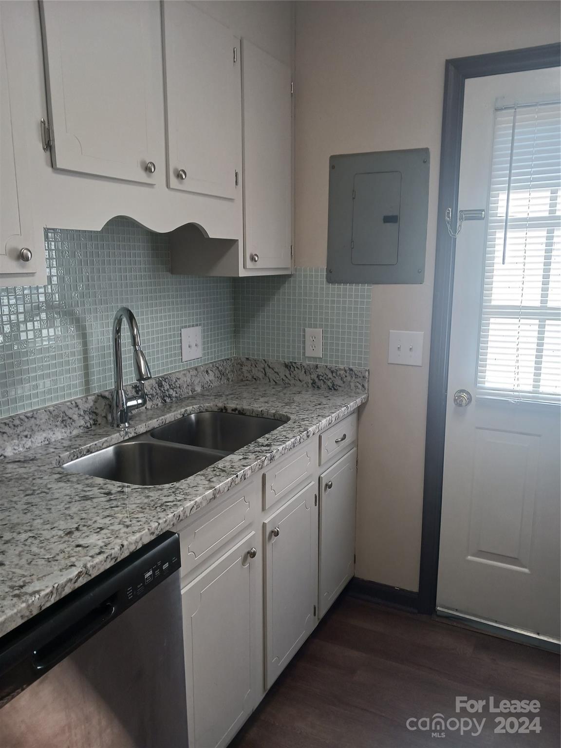 a kitchen with granite countertop white cabinets and a sink