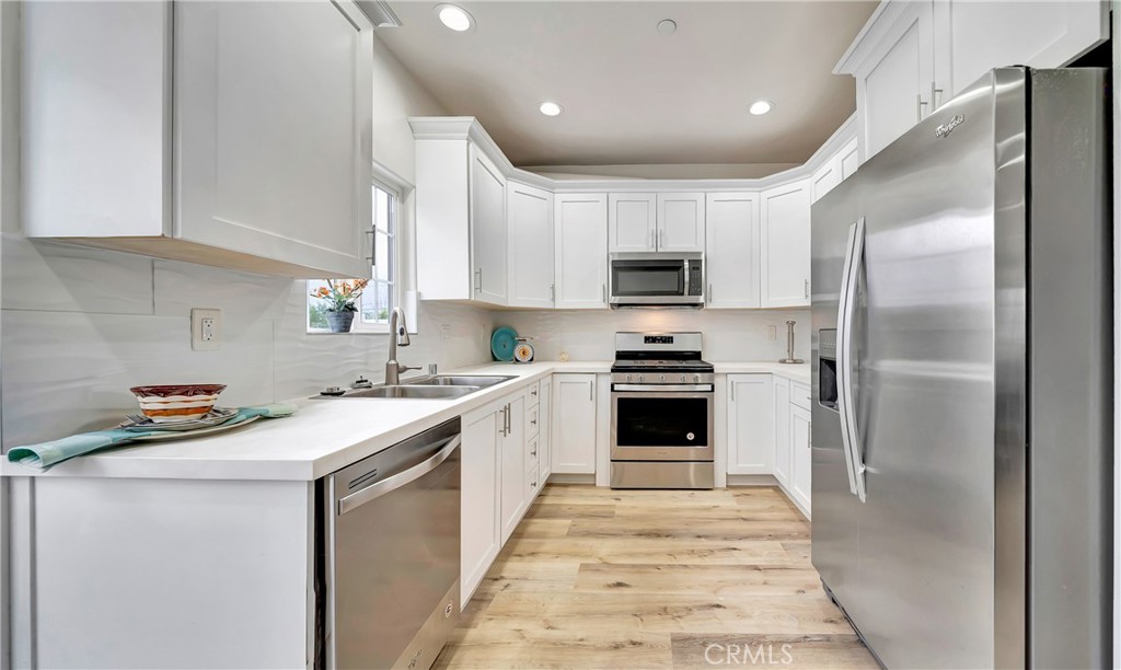 a kitchen with a sink a counter top space stainless steel appliances and cabinets