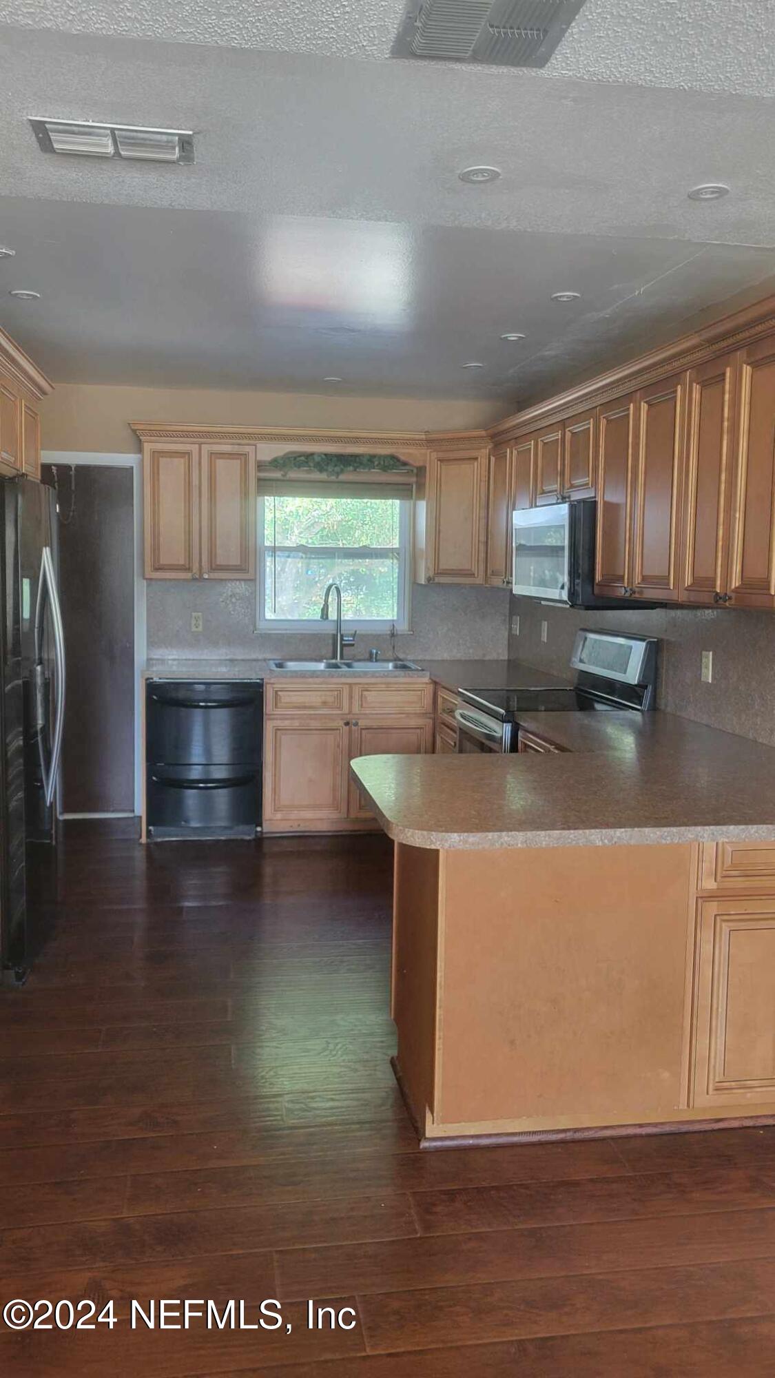 a kitchen with stainless steel appliances granite countertop a sink window and cabinets