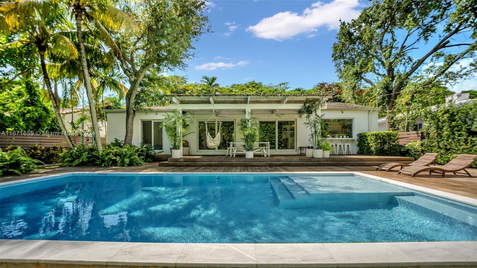 a view of swimming pool with outdoor seating and trees in the background