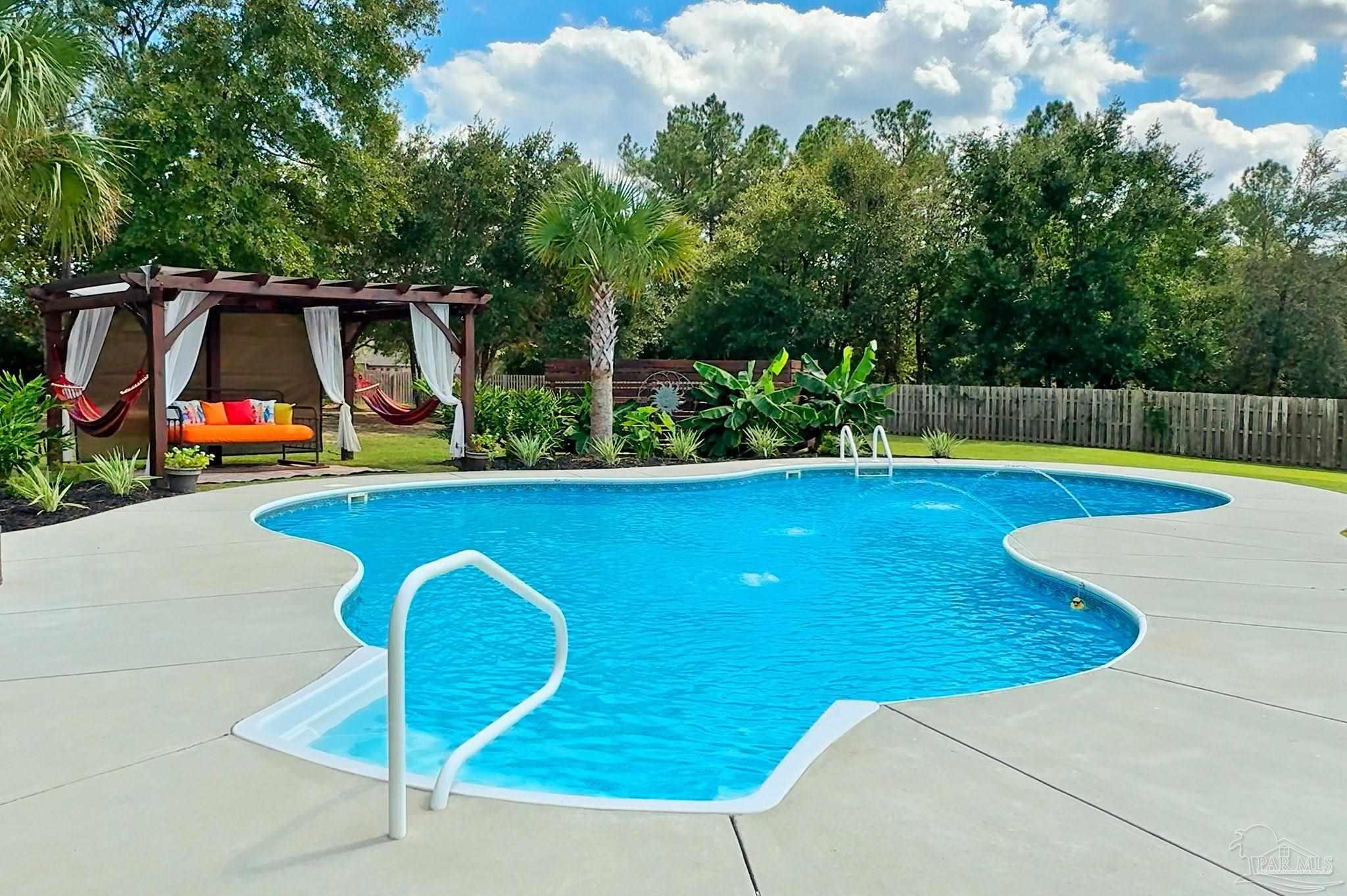 a view of a swimming pool with a yard and plants