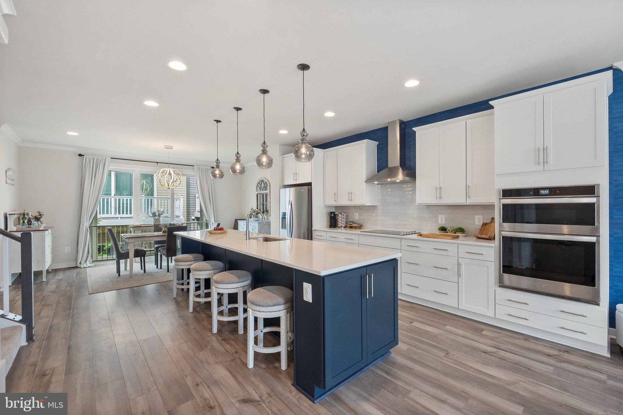 a kitchen with stainless steel appliances kitchen island granite countertop a table chairs sink and cabinets