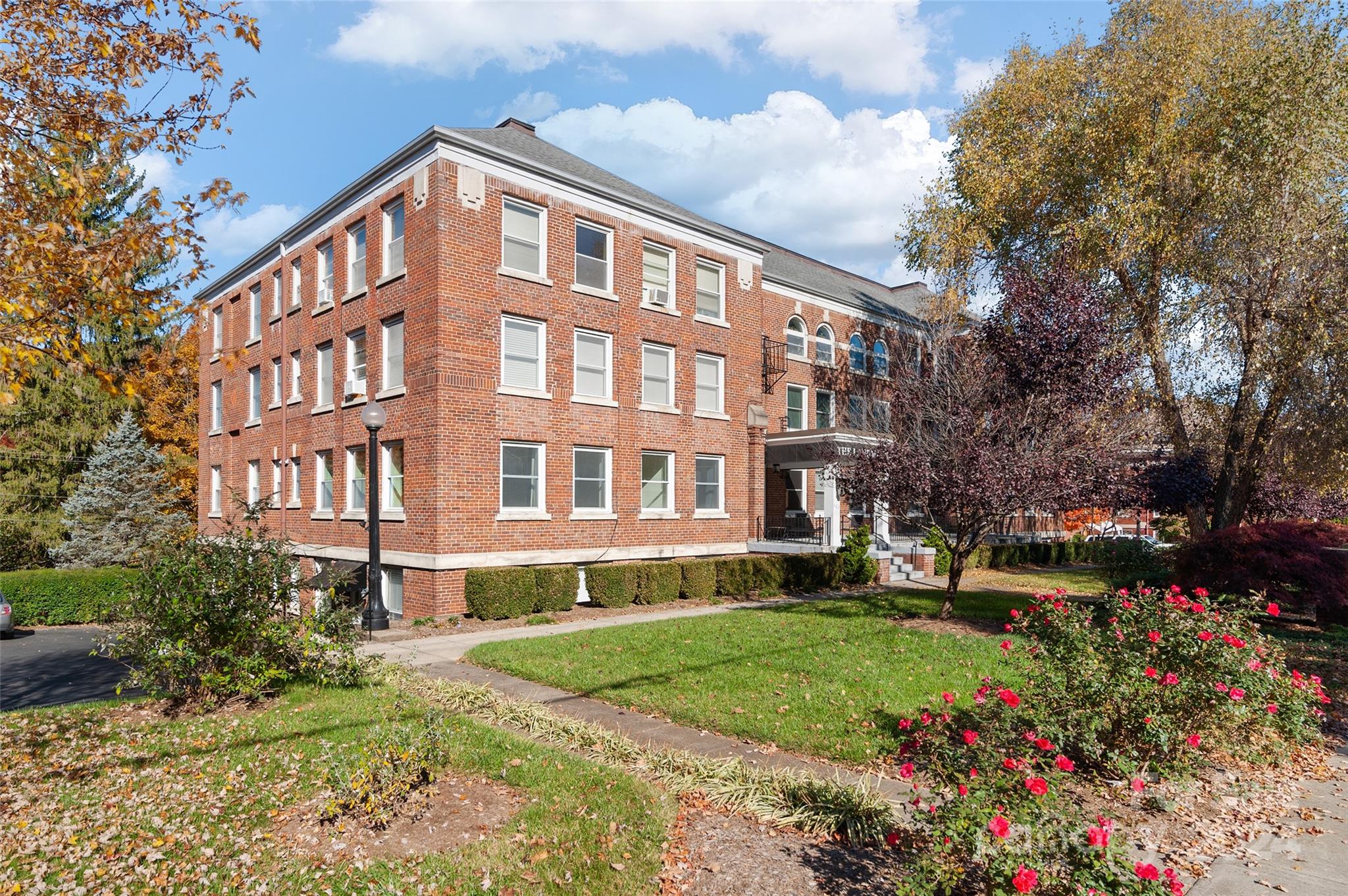 a front view of a building with garden and trees