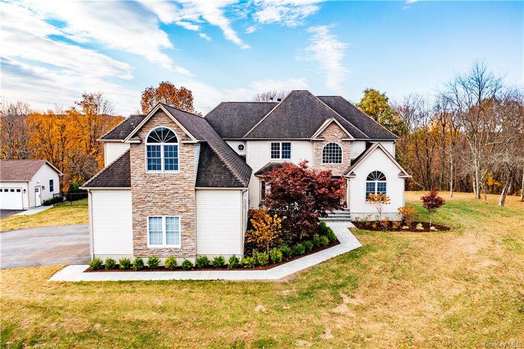 View of front of house with an outbuilding, a garage, and a front lawn