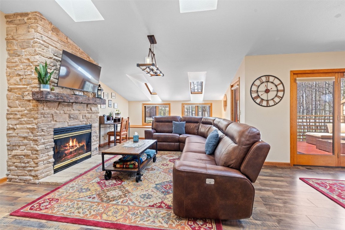 Living room featuring a fireplace, hardwood / wood-style floors, and lofted ceiling with skylight