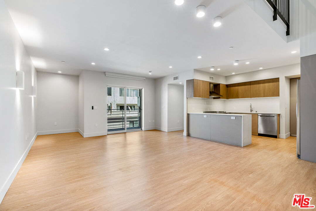 a view of kitchen with refrigerator and white cabinets