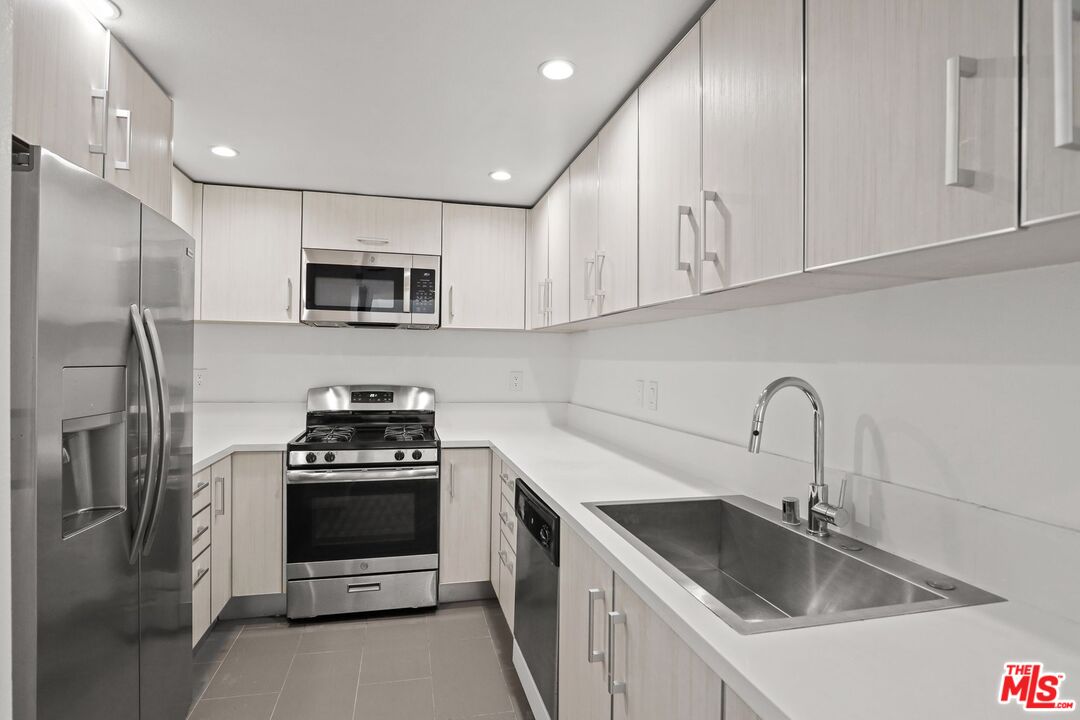 a kitchen with stainless steel appliances granite countertop a sink stove a refrigerator and a sink