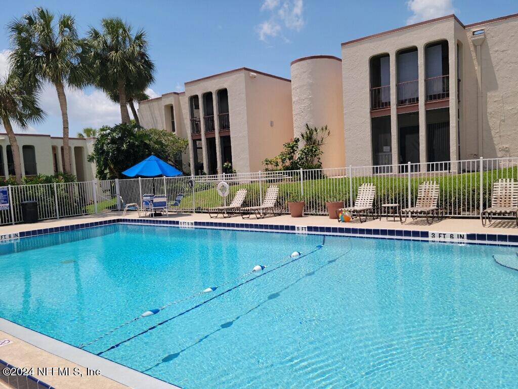 a view of a house with a swimming pool and a chair and table in the patio