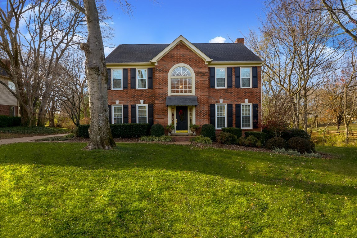 a front view of a house with garden and trees