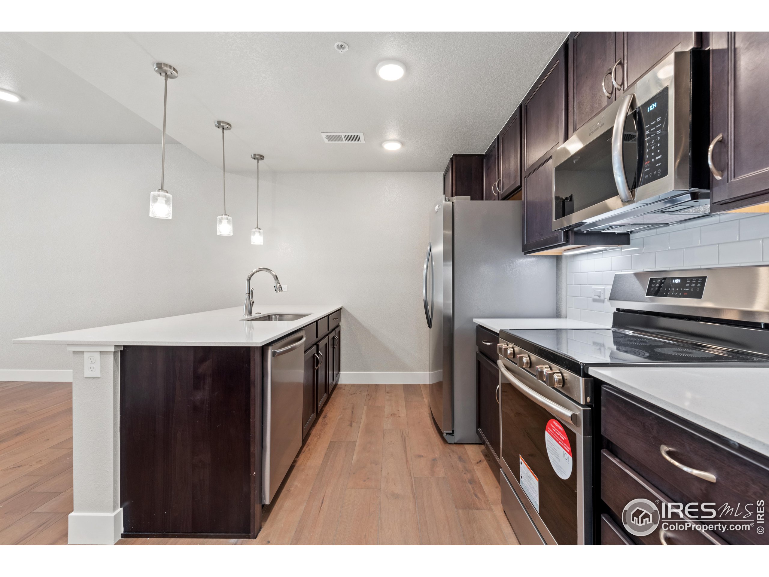 a kitchen with stainless steel appliances granite countertop a sink a stove and a wooden floors