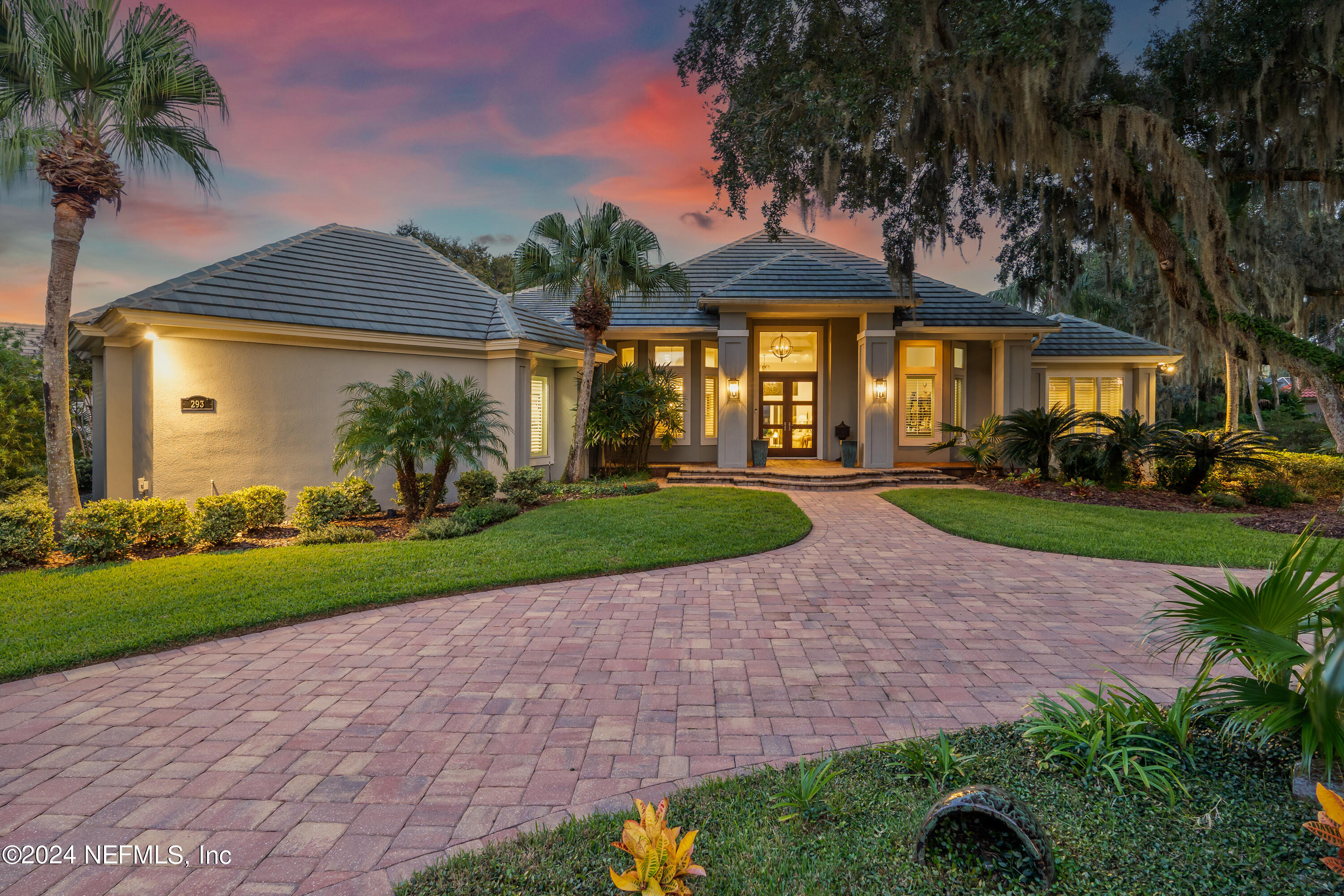 a front view of a house with a yard and potted plants