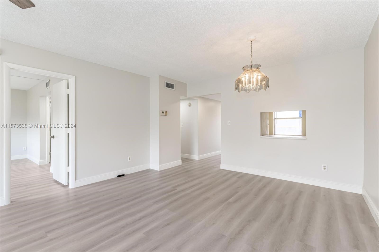 an empty room with wooden floor and chandelier