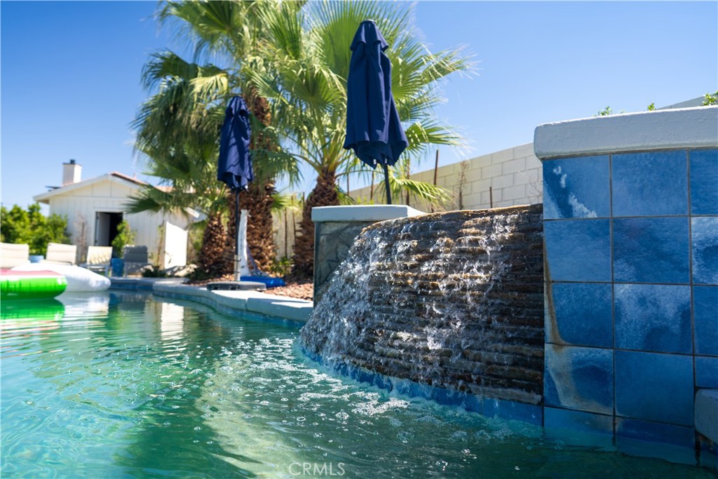 a view of swimming pool with a table and chairs under an umbrella