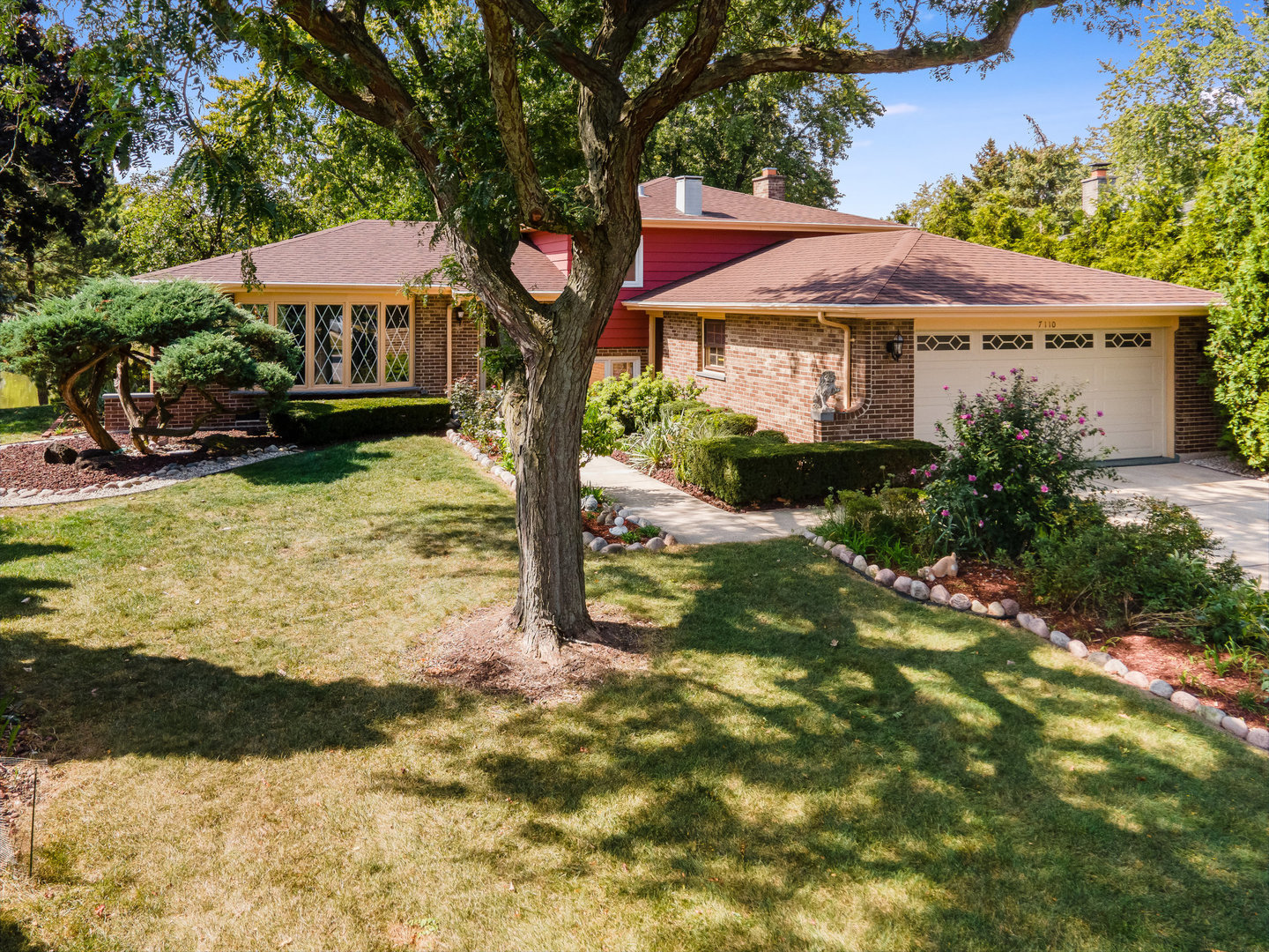 a view of a house with backyard garden and tree