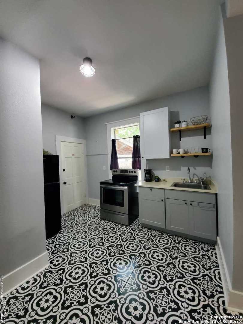 a kitchen with a sink a stove top oven and cabinets