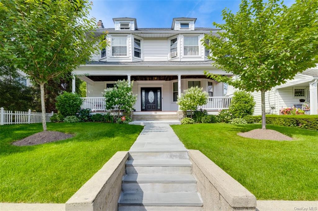 a front view of a house with a yard and potted plants